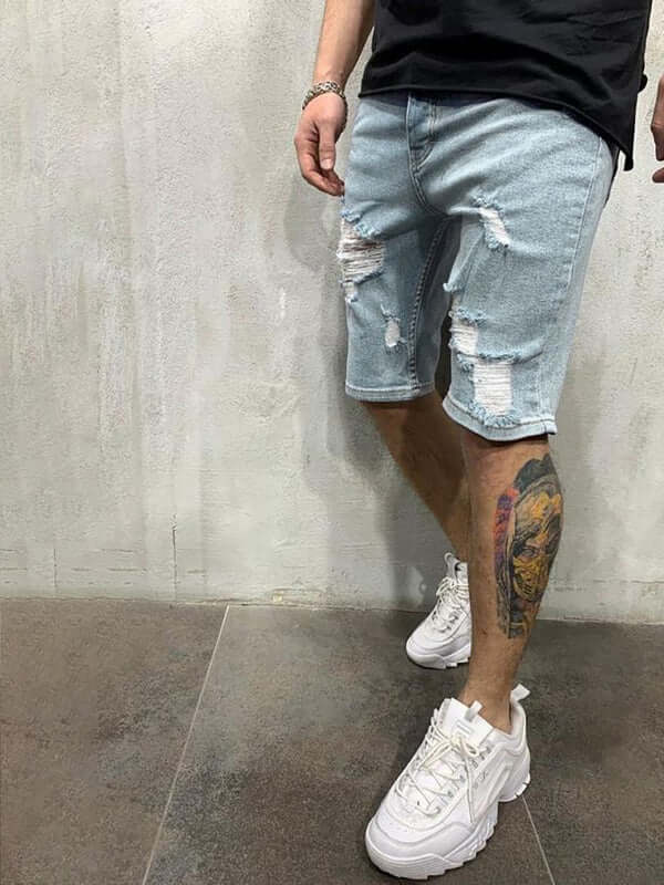 Man wearing Averra Ripped Short Jeans, showcasing a stylish streetwear look with distressed denim shorts and white sneakers.