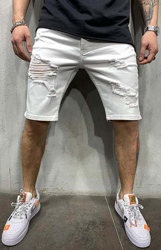 A man wearing Averra Ripped Short Jeans in white, showcasing trendy streetwear denim with stylish rips and casual sneakers.