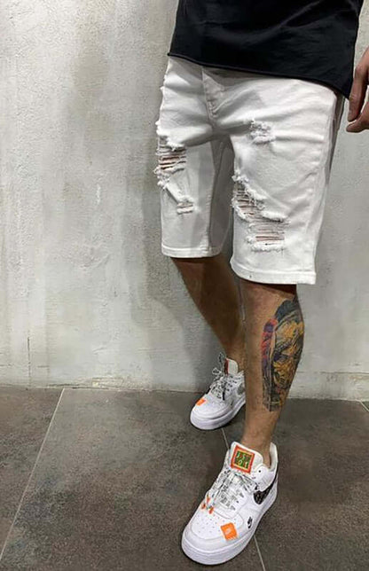 Man wearing Averra ripped white short jeans, styled with trendy sneakers, perfect for streetwear fashion.